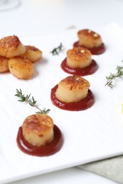 Photo of Delicious fried scallops with tomato sauce and lemon served on white table