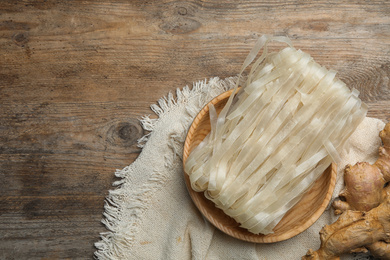 Rice noodles and ginger on wooden table, flat lay