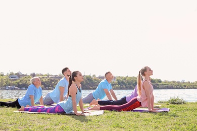 Photo of Group of people practicing yoga near river on sunny day