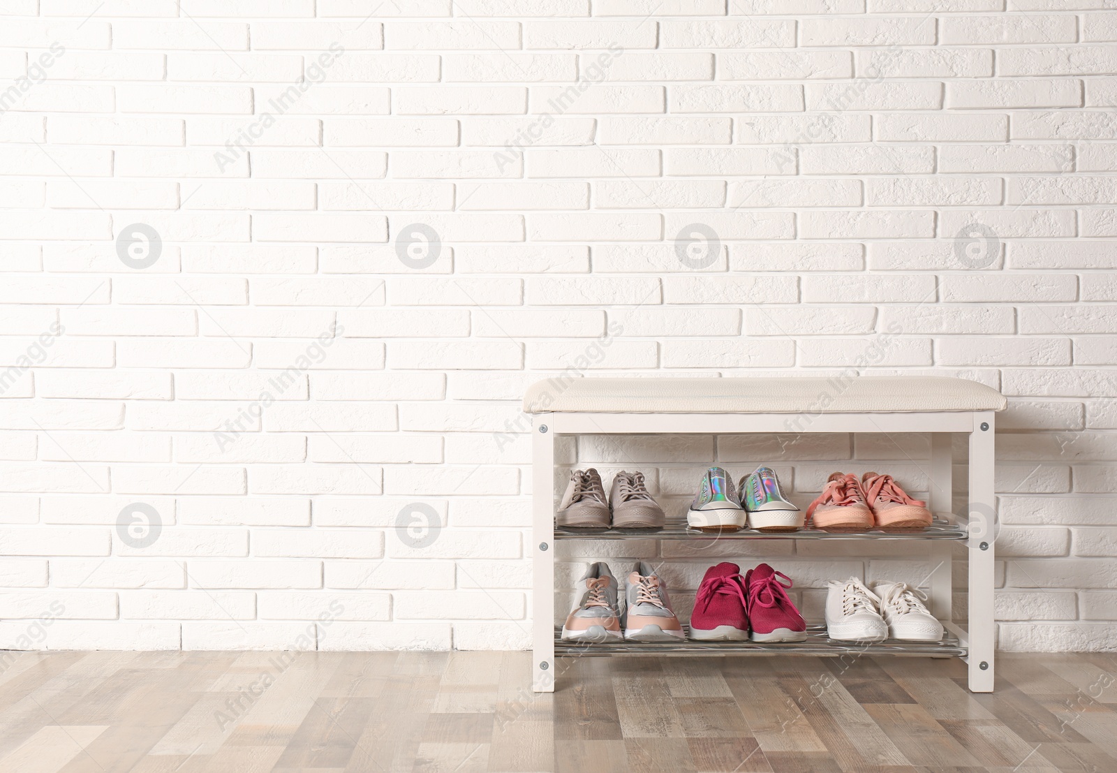 Photo of Shoe storage bench with different sneakers near brick wall, space for text