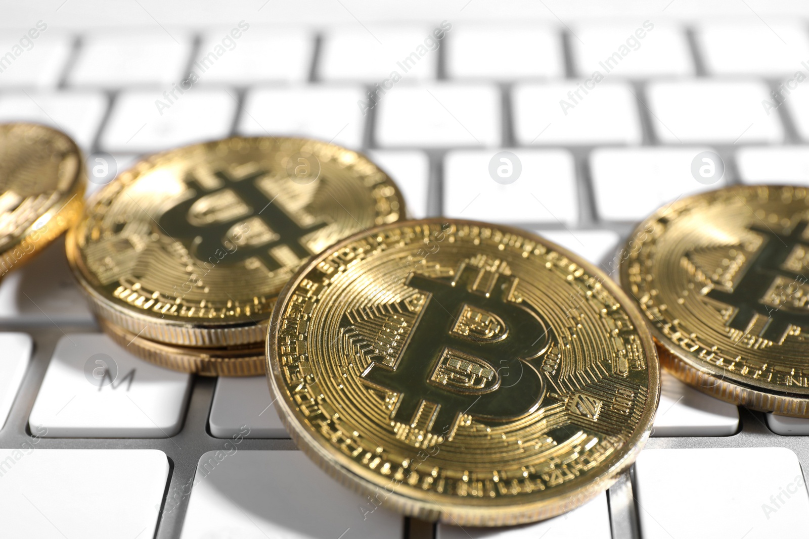 Photo of Golden bitcoins on white computer keyboard, closeup view