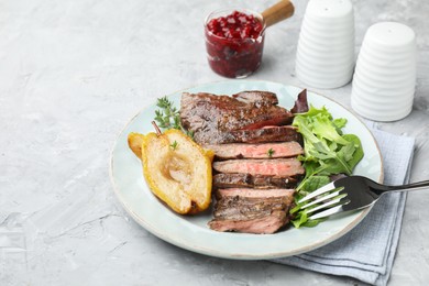 Photo of Delicious roasted beef meat, caramelized pear and greens served on light textured table. Space for text