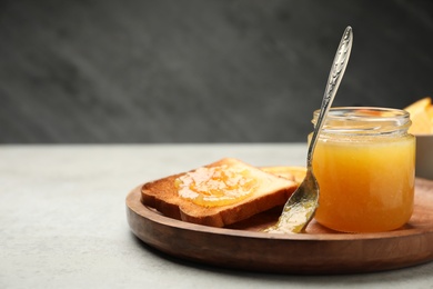 Photo of Delicious toast with orange marmalade on light grey table. Space for text