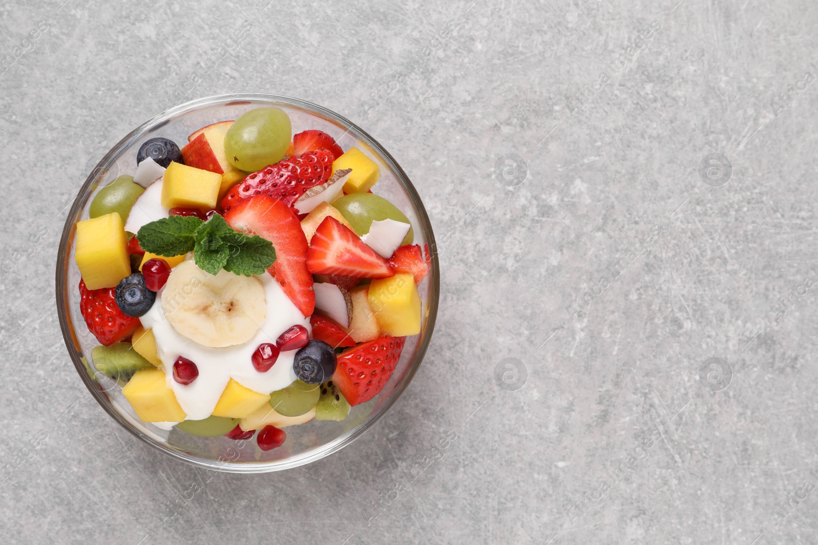 Photo of Delicious fruit salad on light grey table, top view. Space for text