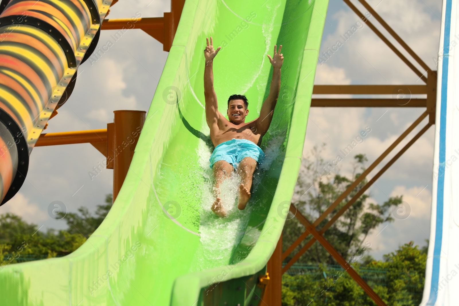 Photo of Man on slide at water park. Summer vacation