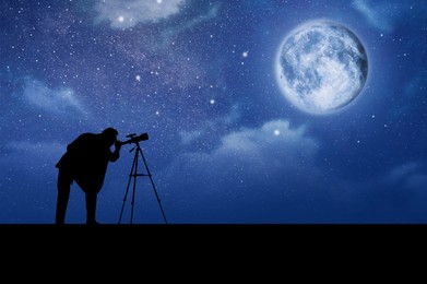Astronomer looking at moon and stars through telescope outdoors
