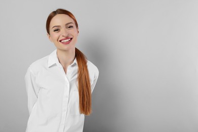 Portrait of beautiful young woman on light gray background, space for text