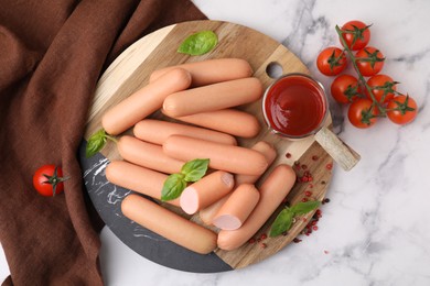 Photo of Delicious boiled sausages with spices, sauce and tomatoes on white marble table, flat lay