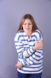 Young woman having heart attack on color background