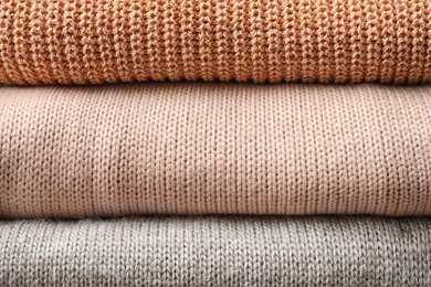 Photo of Stack of warm knitted clothes as background