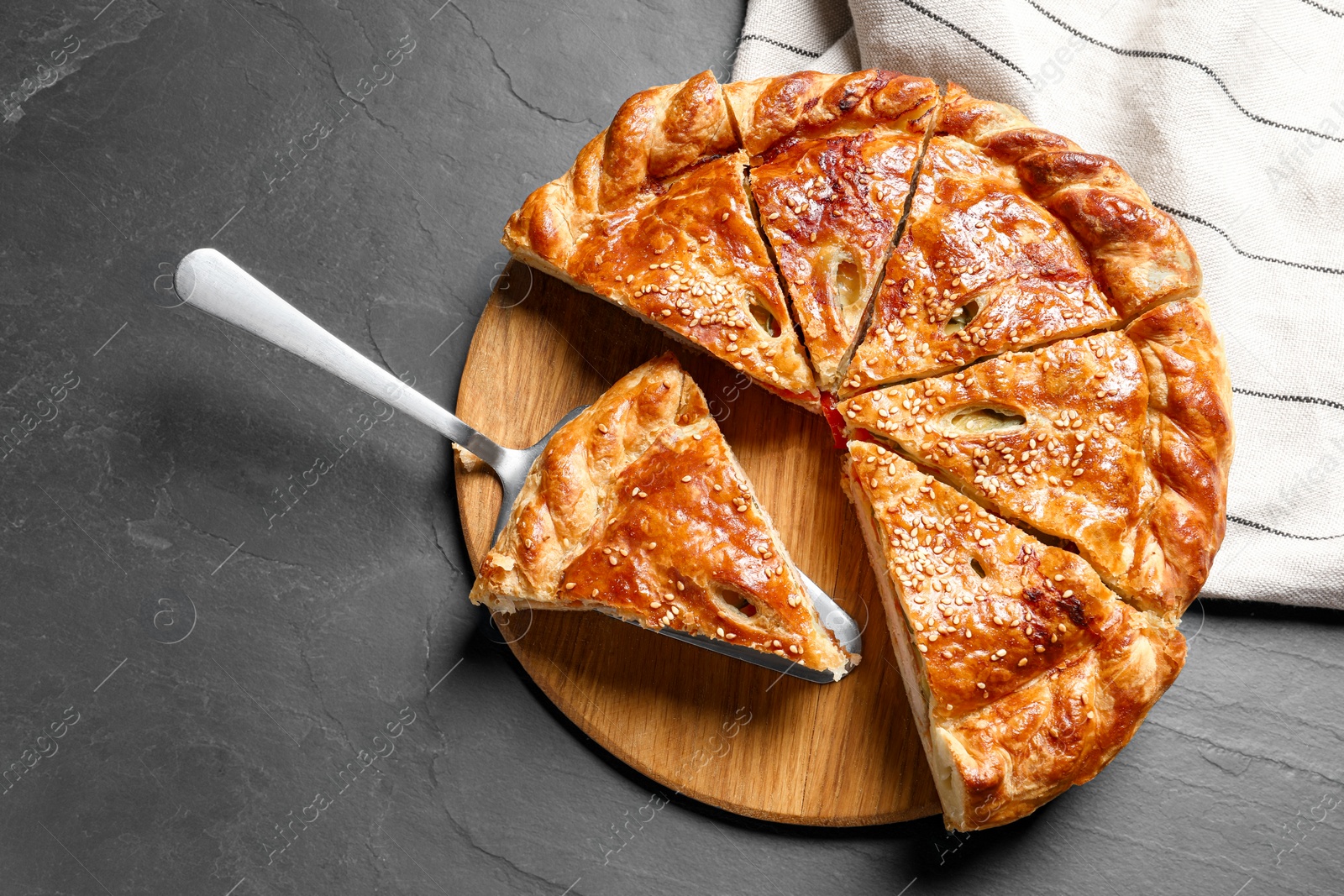 Photo of Cut delicious homemade pie and server on black table, top view