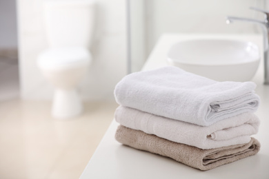 Photo of Stack of fresh towels on countertop in bathroom. Space for text