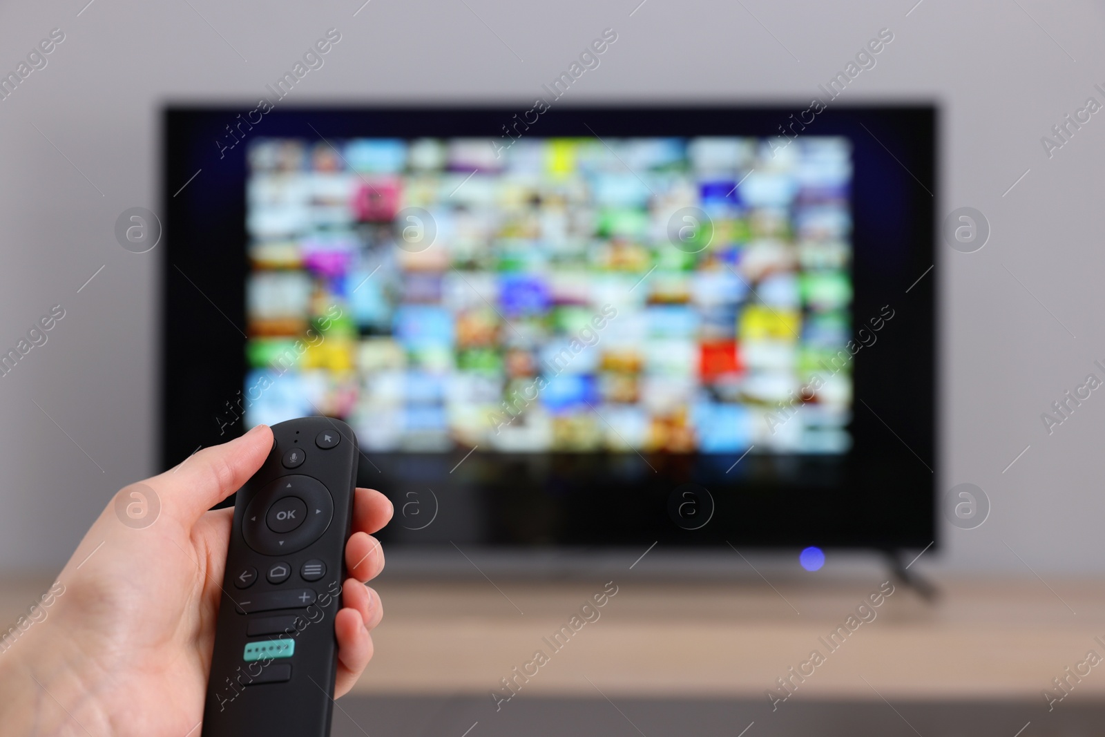 Photo of Woman switching channels on TV set with remote control at home, closeup. Space for text