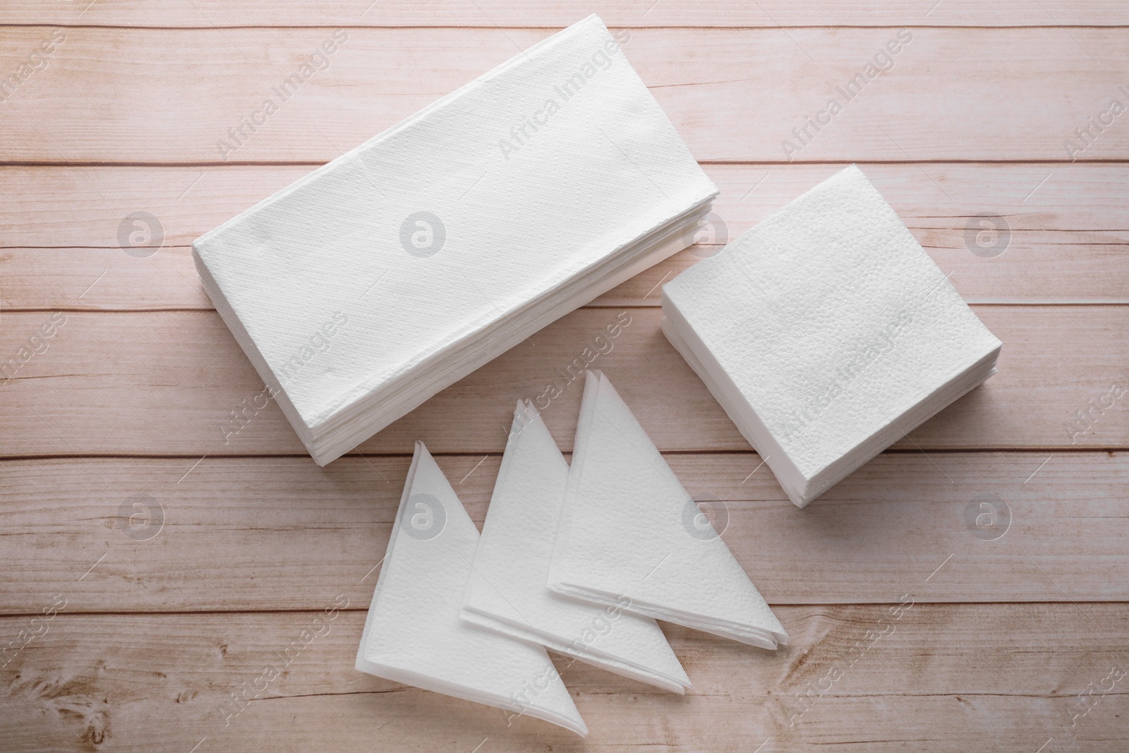 Photo of Clean paper towels and tissues on light wooden table, flat lay