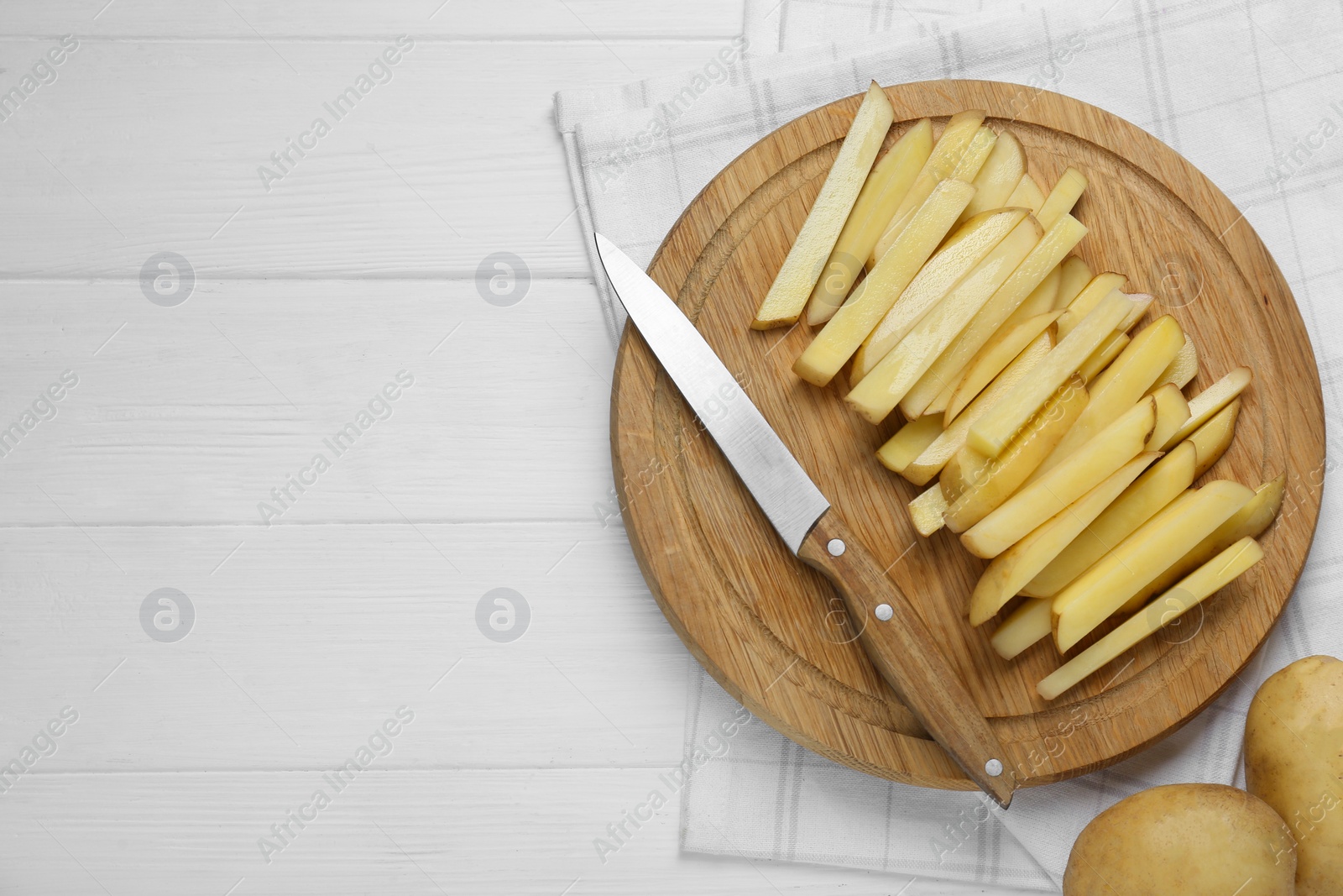 Photo of Cut raw potatoes on white wooden table, top view. Space for text