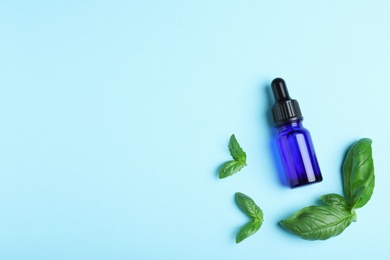 Flat lay composition with basil essential oil and space for text on light blue background