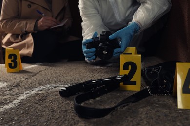 Photo of Investigator and criminologist working at crime scene outdoors, closeup