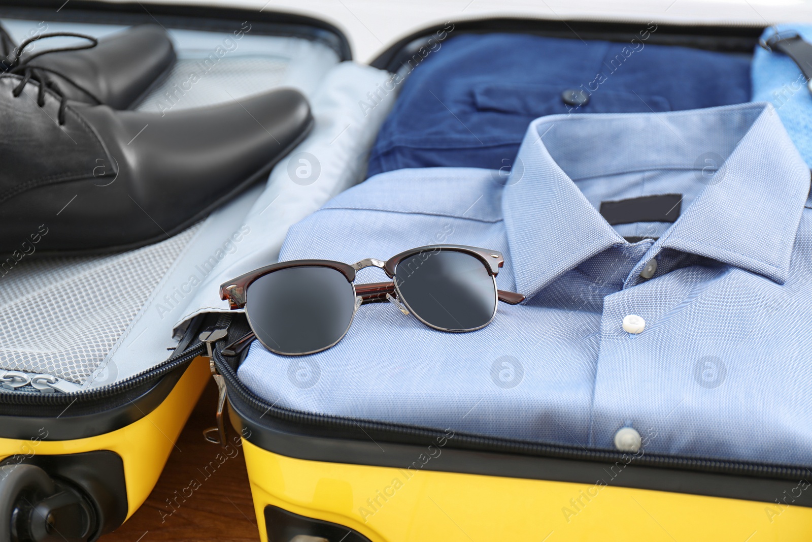 Photo of Open suitcase with clothing, shoes and accessories, closeup