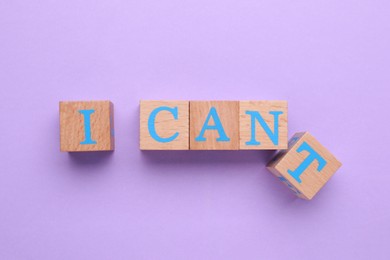 Motivation concept. Changing phrase from I Can't into I Can by removing wooden cube with letter T on violet background, top view