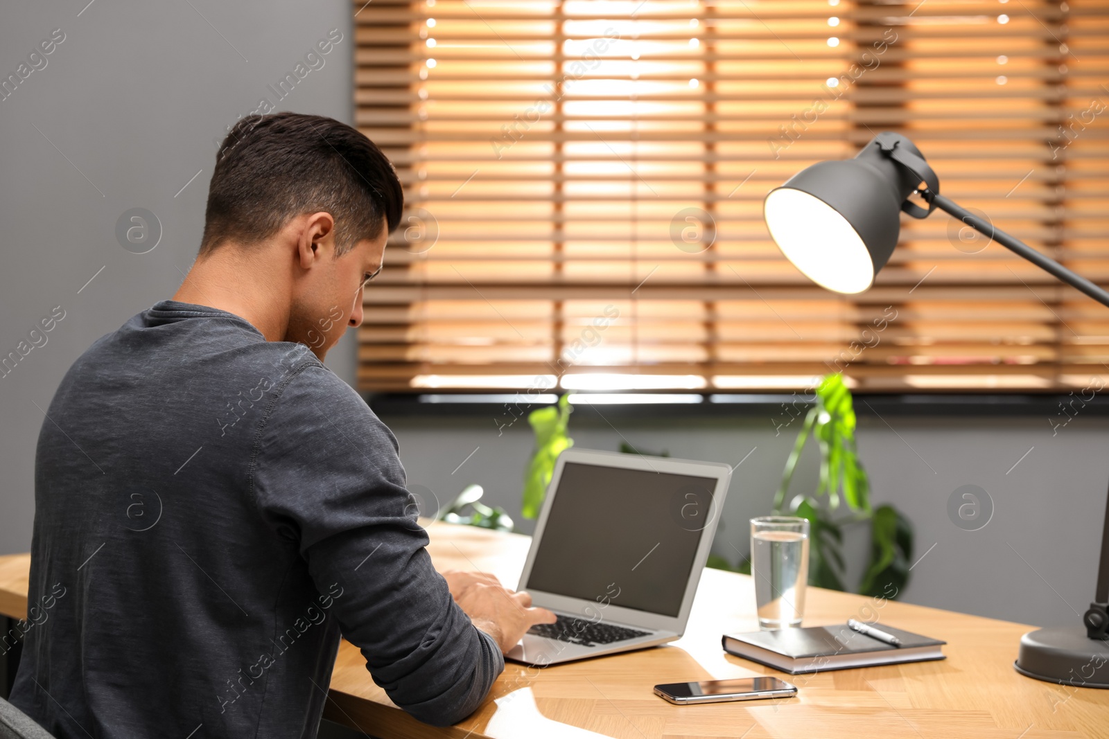 Photo of Man using laptop for search at wooden table in office