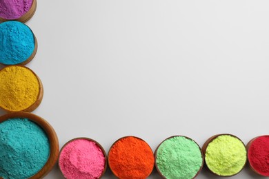 Photo of Colorful powders in bowls on light background, flat lay with space for text. Holi festival celebration