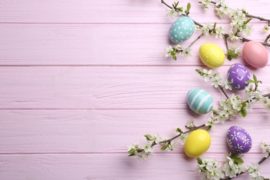 Photo of Flat lay composition with painted Easter eggs and blossoming branches on wooden background. Space for text