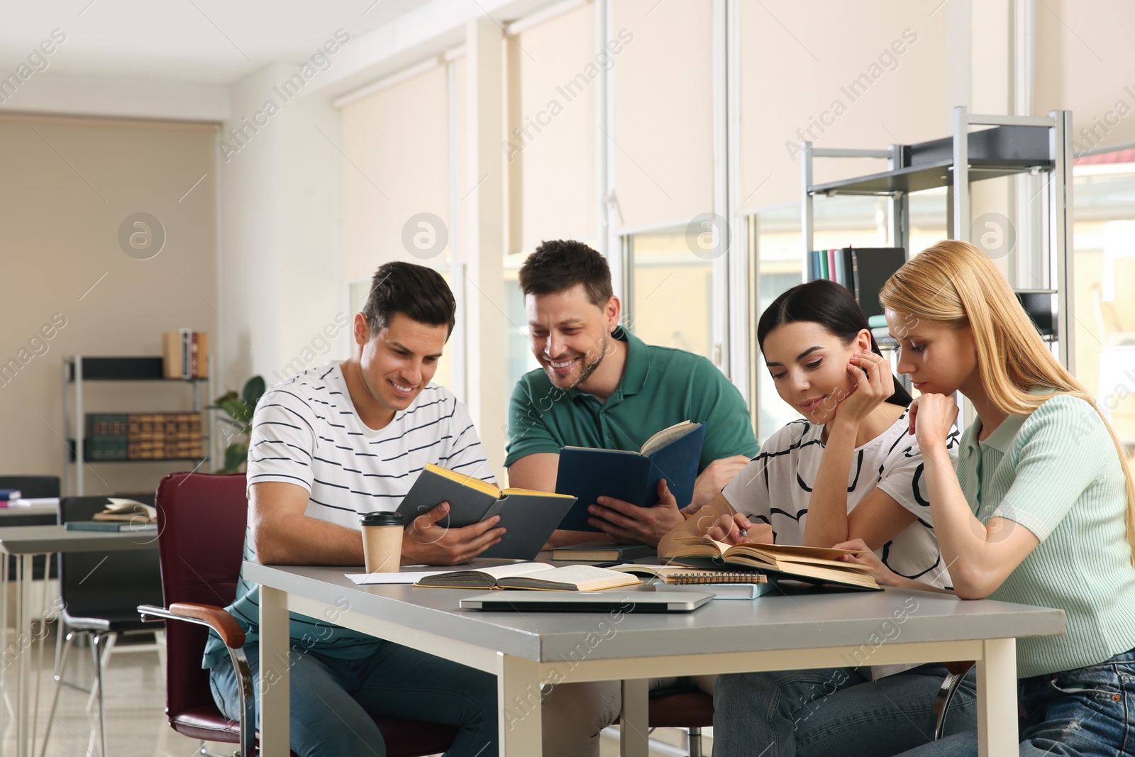 Photo of Young people discussing group project at table in library