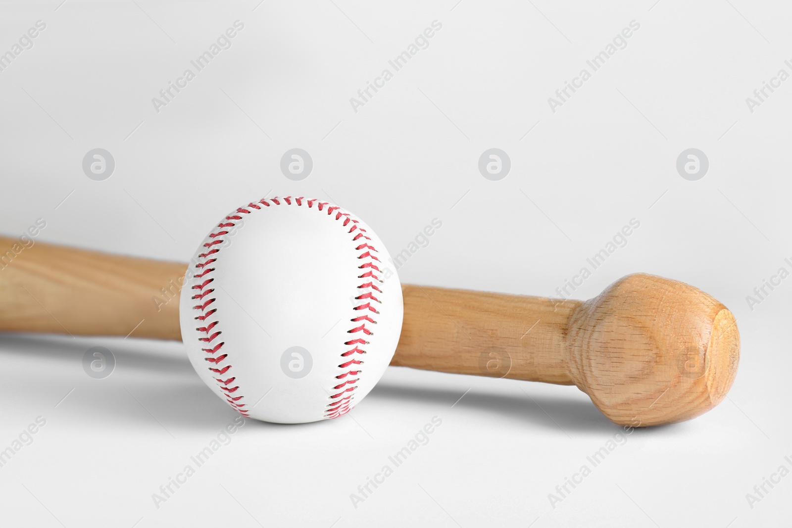 Photo of Wooden baseball bat and ball on white background. Sports equipment