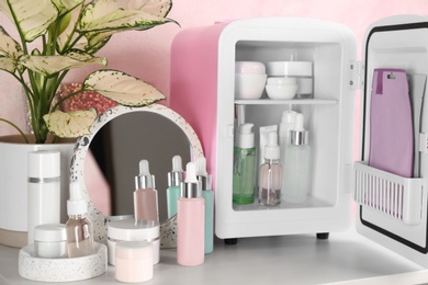 Photo of Cosmetics refrigerator and skin care products on table