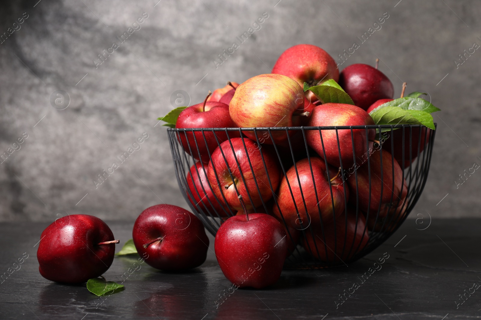 Photo of Fresh ripe red apples in metal bowl on dark grey table