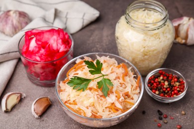 Photo of Delicious sauerkraut prepared according to different recipes and spices on brown table, closeup