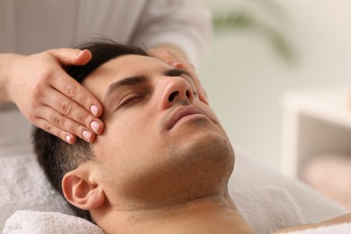 Man receiving facial massage in beauty salon, closeup