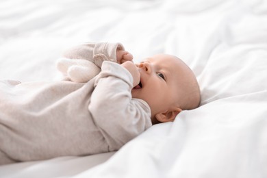 Photo of Cute little baby lying on white sheets