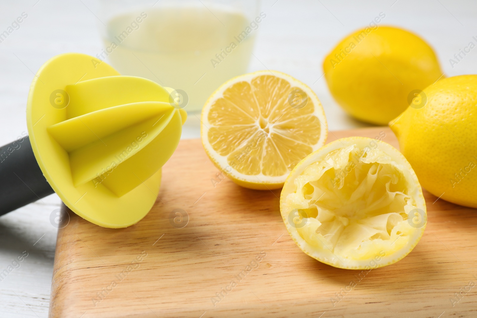 Photo of Citrus juicer and squeezed lemon on wooden board