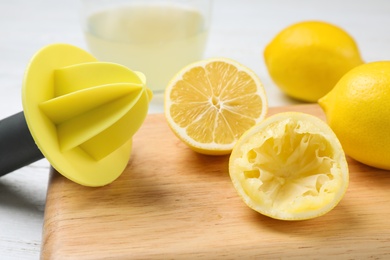 Photo of Citrus juicer and squeezed lemon on wooden board