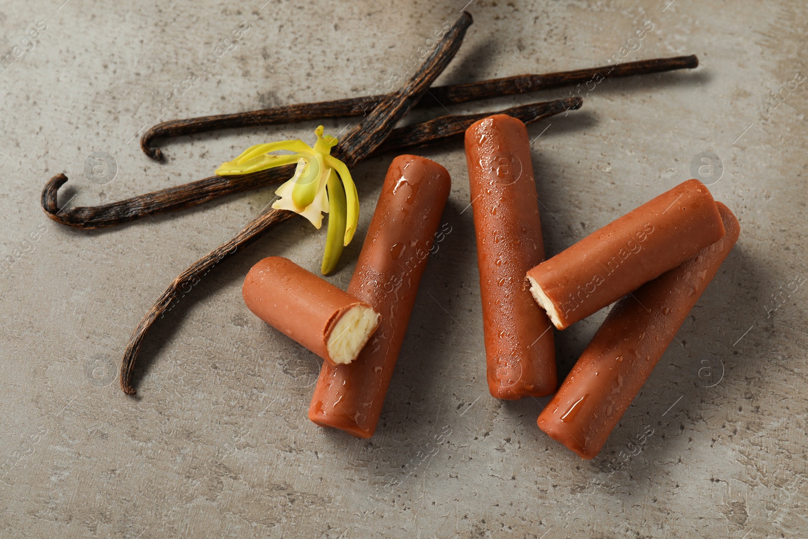 Photo of Glazed curd cheese bars, vanilla pods and flower on grey table, top view