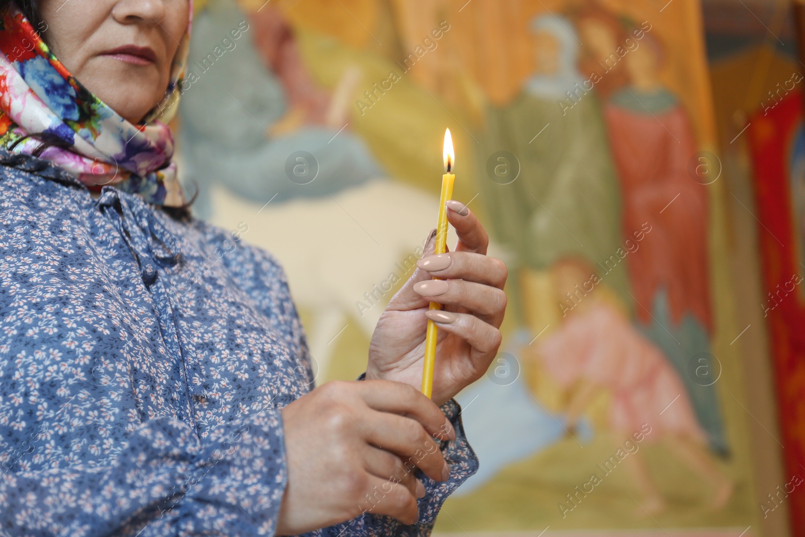 Photo of Mature woman holding candle in church, closeup