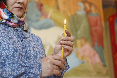Photo of Mature woman holding candle in church, closeup