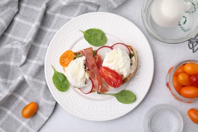 Photo of Delicious sandwich with burrata cheese, ham, radish and tomatoes served on light grey table, flat lay