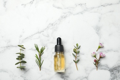 Flat lay composition with bottle of natural tea tree oil on marble table, space for text