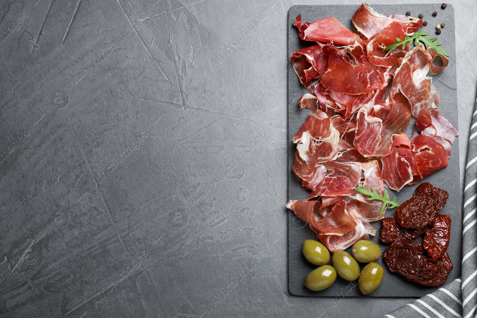 Photo of Tasty prosciutto served on grey table, top view. Space for text