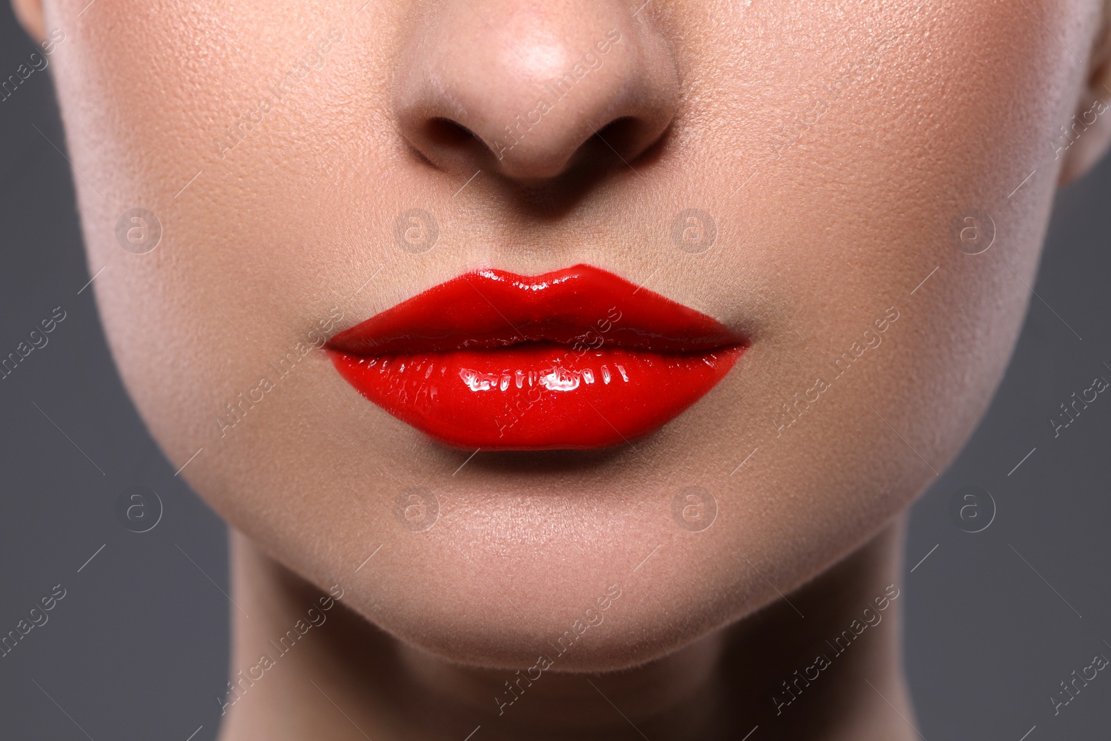 Photo of Young woman with beautiful red lips on grey background, closeup