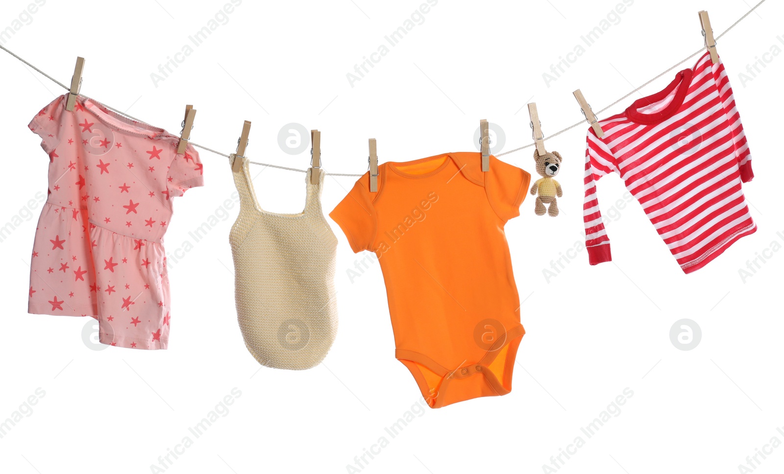 Photo of Different baby clothes and bear toy drying on laundry line against white background