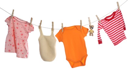 Photo of Different baby clothes and bear toy drying on laundry line against white background