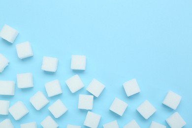 Photo of White sugar cubes on light blue background, top view. Space for text