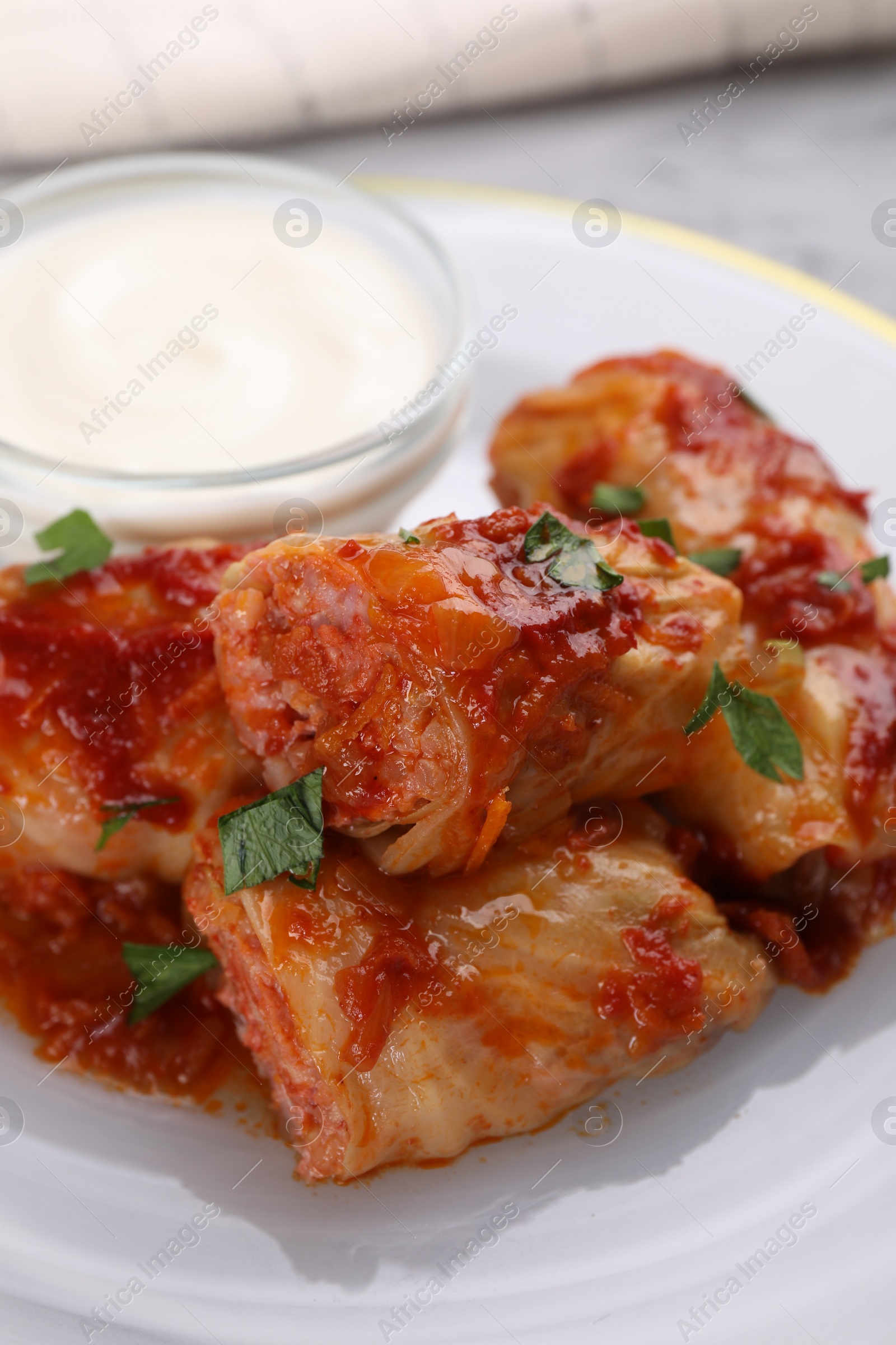 Photo of Delicious stuffed cabbage rolls served with sour cream on plate, closeup