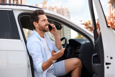 Photo of Happy man talking on smartphone in modern car