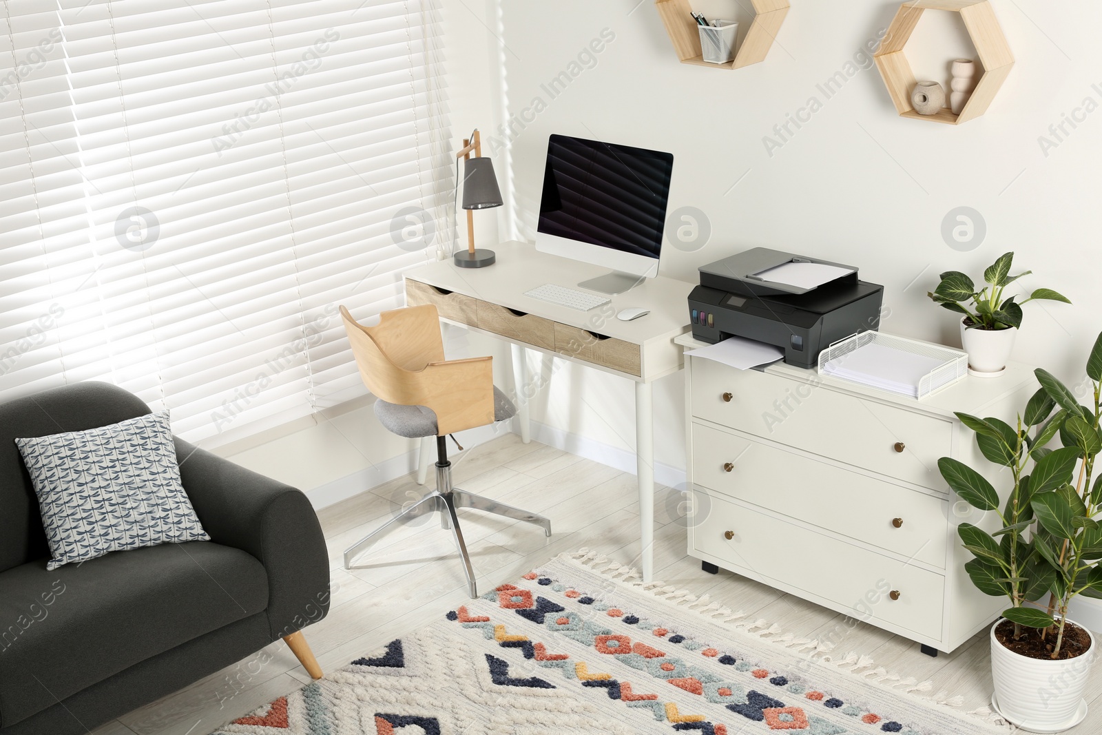 Photo of Stylish workplace with modern computer, printer and lamp