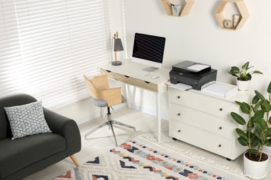 Photo of Stylish workplace with modern computer, printer and lamp