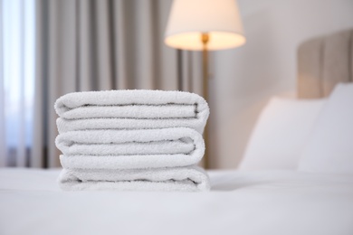 Stack of clean towels on bed indoors